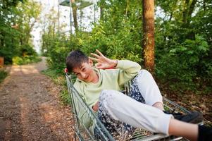 niño sentado en carro con teléfono móvil en el bosque. foto