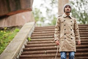 Stylish kuwaiti man at trench coat and hat. photo