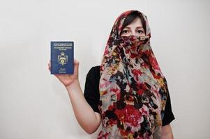 Young arabian muslim woman in hijab clothes hold Hashemite Kingdom of Jordan passport on white wall background, studio portrait. photo