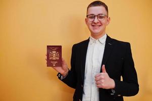Young handsome man holding Georgia passport id over yellow background, happy and show thumb up. photo