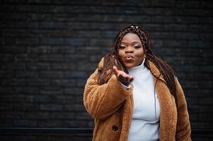 glamorosa mujer afroamericana en pose de cálido abrigo de piel en la calle. foto