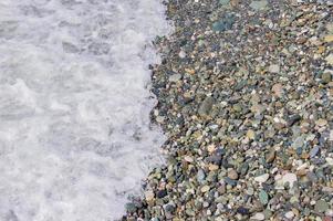 pebble coastline. Seashore with transparent water and small stones photo