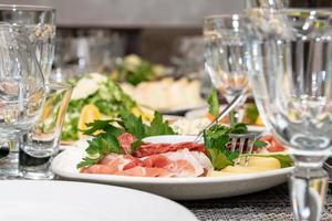 Festive table setting, family dinner with served italian antipasti - marinated salmon, hamon, Carpaccio, pear, basil. Tablescape. photo