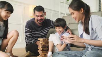 joyeuse activité familiale thaïlandaise asiatique, parents, papa, maman et enfants s'amusent à jouer et de joyeux blocs de jouets en bois ensemble sur le sol du salon, le week-end de loisirs et le style de vie de bien-être domestique. video