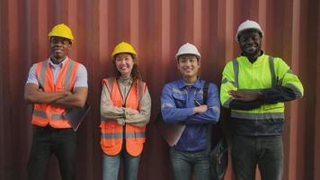 Portrait of a group of multiracial workers team, Black and Asian in safety uniforms, arms crossed, smile and looking at camera on metal sheet background, logistic containers transportation industry. video