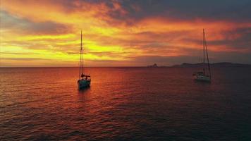 Fliegen Sie über den Ozean zwischen Yachten in orangefarbenem und gelbem Sonnenuntergangslicht video