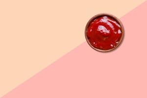 Close up view red tomatoes ketchup isolated on pink background. photo