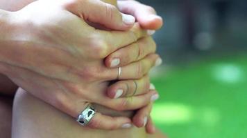 Close up of feminine hands with silver rings clasped together on knee video