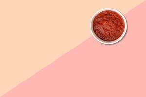 Close up view red tomatoes ketchup isolated on pink background. photo