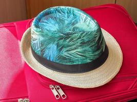 Summer hat from sun lies on red suitcase for travel. photo