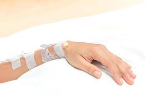 cierre el goteo de solución salina en la mano del paciente en el hospital foto