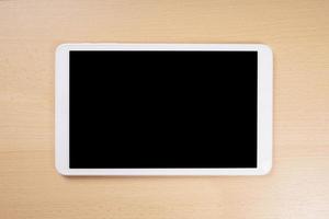 Tablet PC con pantalla en blanco en el escritorio de madera foto