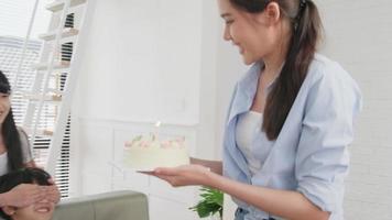 Happy Asian Thai family, young son is surprised with birthday cake, gift, blows out candle, and celebrates party with parents together in living room, wellbeing domestic home event lifestyle. video