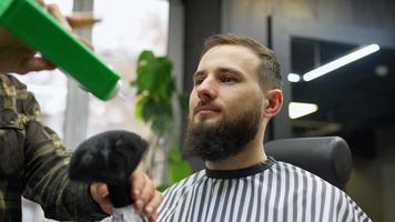 barbiere polveri il viso di un' maschio cliente con grande spazzola