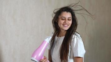 mujer secando el cabello haciendo contacto visual y sonriendo luego saca la lengua video