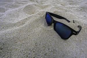 Lone sunglasses lying on a sandy beach photo