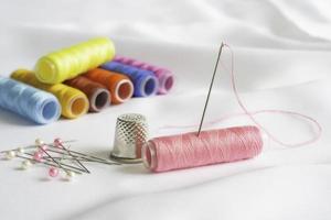 Needle, pins, thimble and colorful spools of thread photo