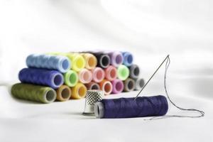 Needle,thimble and colorful spools of thread photo