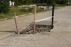 Bad automobile, pedestrian road with a large pit and a signal fence. photo