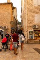 Budva, Montenegro - October 20, 2020 - Fragment of the old town, old houses with walking tourists, a very narrow street, cafes, shops. photo