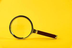 Magnifying glass in a gold frame on a yellow background. Copy space. photo