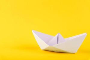 White paper boat on a yellow background. Copy space. photo