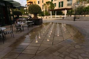 Small contact fountain with illumination near a cafe on the street photo