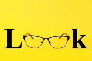 Glasses, text Look, on a yellow background. Copy space photo