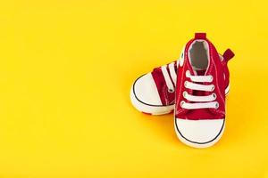 A pair of red sneakers. sneakers for a boy on a yellow background. Travel concept with kids, kids lifestyle. Copy space. photo