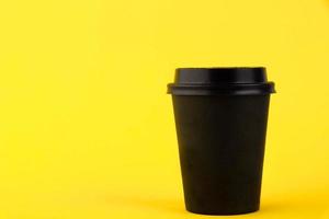 Black paper eco cup, coffee paper cup on yellow background. Mockup for your advertisement photo