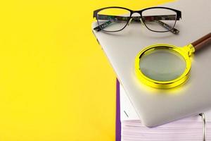 Office, folder with documents awaiting verification, magnifying glass, on a yellow background. Business and education concept. Copy space photo