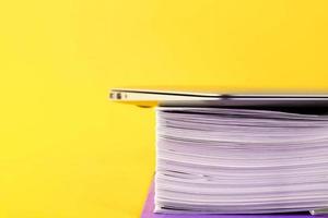 Office, folder with documents awaiting verification, laptop on a yellow background. Business and education concept. Copy space. Selective focus. photo