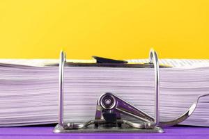 Close up of a pile of unfinished documents awaiting verification on a yellow background. Business and education concept. Copy space photo