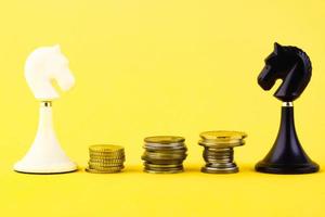 Black and white chess piece of a horse, with coins in the form of steps on a yellow background. Business concept. Game, strategy, wisdom, determination. Copy space. photo