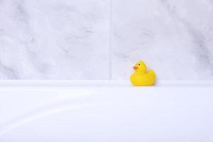 Close-up of toys, yellow duckling, in a bathroom on a background of gray tiles. Copy space photo