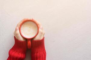 Top view hands holding red cappuccino mug. The atmosphere of sunny autumn. Background with copy space. photo