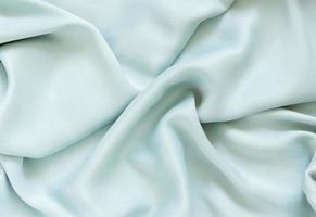 Silk draped mint fabric with pleats and glitter. Textured background of delicate green color. photo