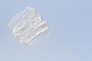 White cream texture on a blue background and SPF 50 text. The concept of skin protection, a banner with copy space. photo