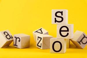 SEO, search engine optimization, text wooden cube blocks on yellow background. Idea, vision, strategy, analysis, keyword and content concept photo