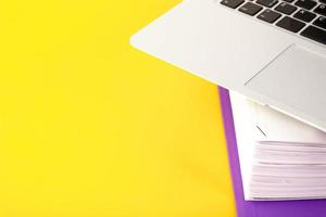 Office, folder with documents awaiting verification, laptop on a yellow background. Business and education concept. Copy space. Selective focus. photo