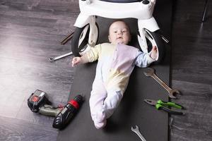 niño mecánico repara la suspensión de un carro de bebé. reparamos todo lo que viaja. humor, desafío. foto