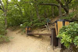 Tourist resting place, route in a mountain forest, a bench with a trash can. photo