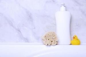 Children's hygiene products concept. Yellow duckling in the bathroom on a background of gray tiles. Copy space photo