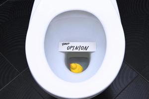 The words, the phrase YOUR OPINION is written on the note card, and the yellow duck is floating in the toilet as a reminder of the importance of customer feedback. photo