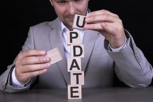 UPDATE, the word is written on wooden cubes, blocks on the background of a man, a businessman in a gray suit. photo