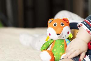 Hand of a child lying on a bed with a toy. Close-up of a palm. Fatherhood and children protection day concept. photo