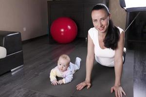 una hermosa joven madre con su hijo practica deportes, yoga, ejercicios, educación física. el concepto de recuperación física después del parto. foto