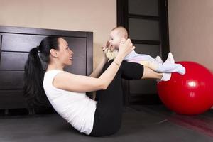el niño juega, hace ejercicios, hace gimnasia con su madre en casa. foto