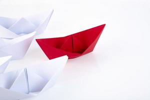 one red paper boat between many white paper boats. Copy space. photo