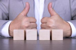 A businessman adds four wooden cubes with empty space for icons, free space for letters, numbers, symbols or labels. photo